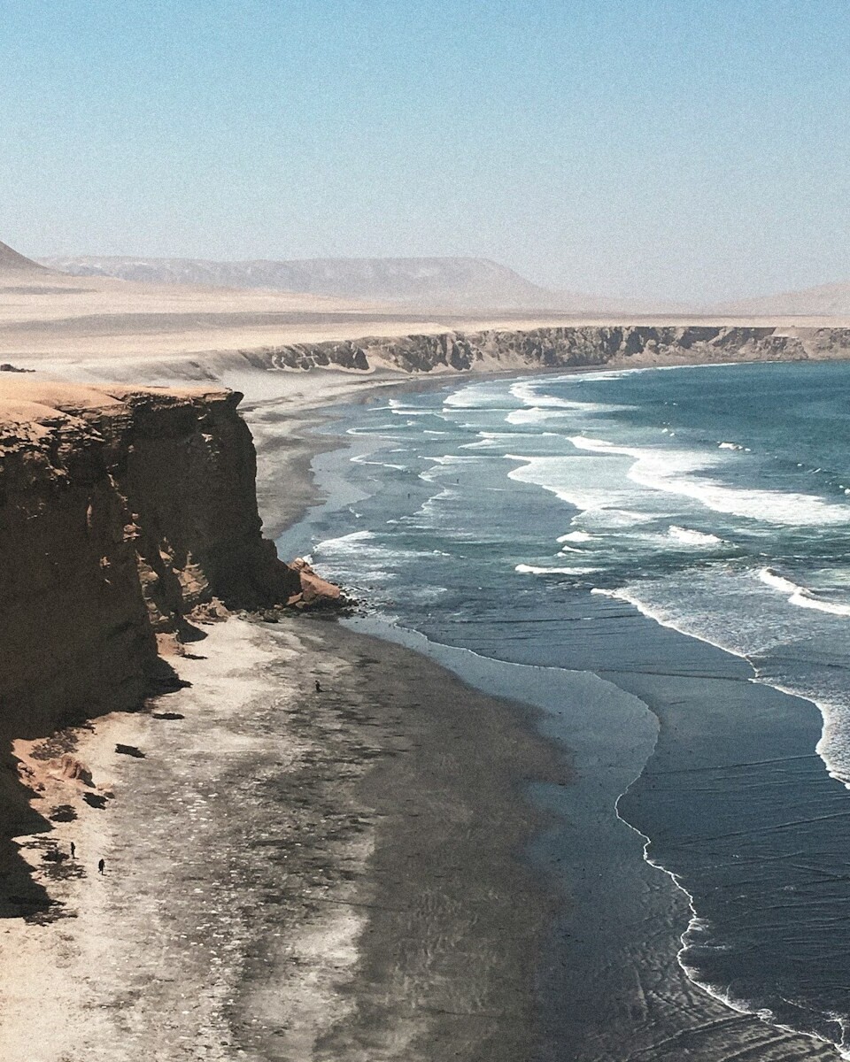 brown rocky mountain beside blue sea under blue sky during daytime