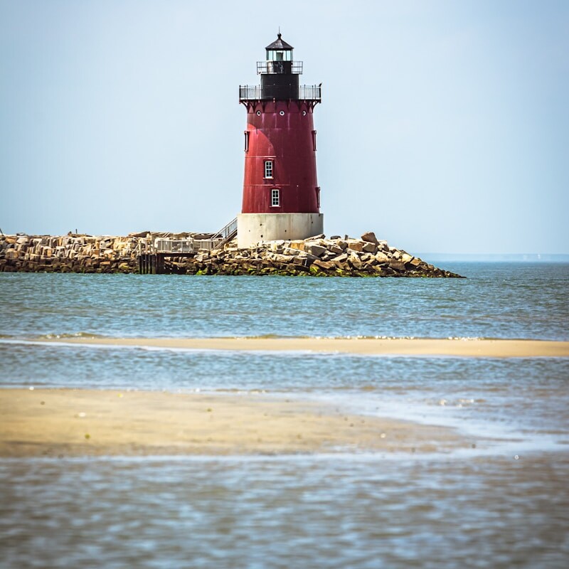 A red and white light house sitting on top of a small island